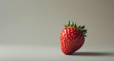 Ripe red strawberry sitting on a soft gray background with ample negative space for text or design highlighting its vibrant texture and shape. photo