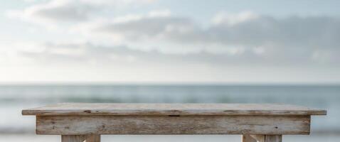 Weathered Wooden Table Overlooking Blurred Beach and Sea Under Cloudy Sky Ideal for Relaxation or Oceanfront Dining Concepts. photo