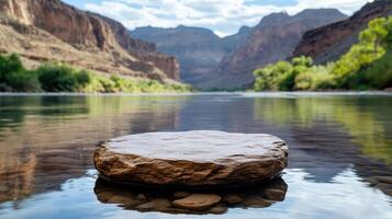 serene river scene featuring flat rock in calm water, surrounded by mountains photo
