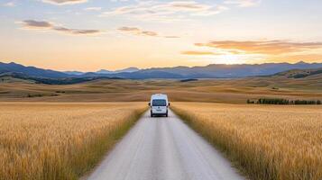 van travels down winding road through golden fields at sunset photo