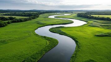 Winding river flows through lush green fields under bright sky photo