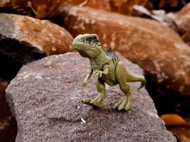 A toy dinosaur on a rock photo