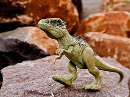A toy dinosaur on a rock photo