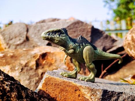 A toy dinosaur is standing on a rock photo