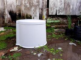 A white trash can sitting in the mud photo