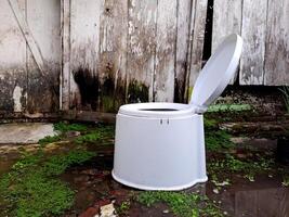 A white toilet sitting in the mud photo