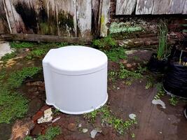 A white trash can sitting in the middle of a yard photo