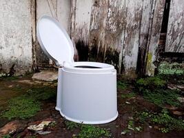 A white toilet sitting in front of a wooden wall photo