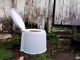 A white toilet sitting in the mud outside photo