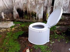A white toilet sitting in the grass next to a wooden fence photo