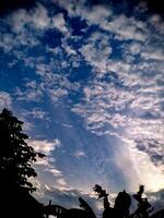 A silhouette of a person standing under a blue sky photo