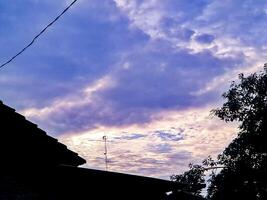 A sky with clouds and a house with a clock photo
