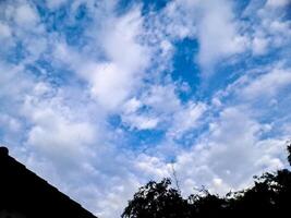 A blue sky with clouds and trees photo