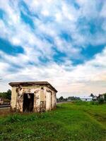 An old abandoned building sits in the middle of a grassy field photo