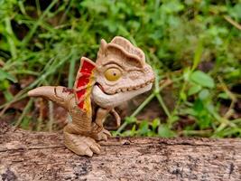 A toy dinosaur is standing on a log photo