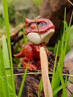 A small toy dinosaur sitting on a log photo