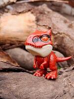 A red toy dinosaur on a log photo