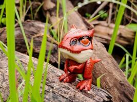 A toy dinosaur standing on a log in the grass photo