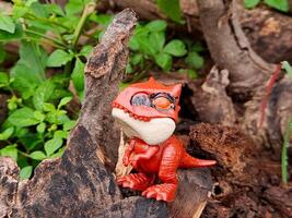 A toy dinosaur is sitting on a log photo