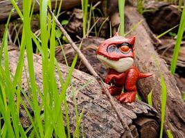 A toy dinosaur standing on a log in the grass photo