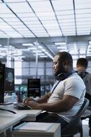 Smiling technician working in high tech workplace providing computing resources for different workloads. Radiant IT specialist tasked with monitoring data center mainframes photo