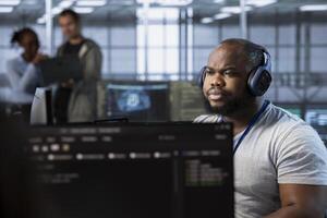 Engineer in server hub listening music, implementing power management solutions to reduce energy consumption. IT expert wearing headphones, hearing songs and integrating new systems in data center photo