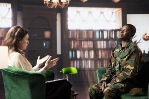 Psychiatrist offering support to combat veteran in counseling session, suffering from anxiety and shell shock. Distraught trooper dealing with war flashbacks, traumatic experiences. photo