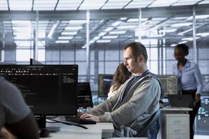 System administrator implements cybersecurity measures to protect data center assets and information. Man in server hub workspace monitoring and analyzing metrics to enhance operational effectiveness photo