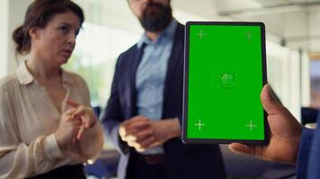 Salesman using green screen tablet to present car addons options to clients, trying to sway them to make purchase. Showroom agent offers extended warranty to customers, holding mockup device, camera B photo