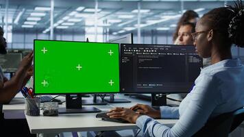 IT technician looking at green screen PC, working in data center, ensuring optimal performance. Employees monitoring energy consumption across server rigs using chroma key monitor, camera B photo