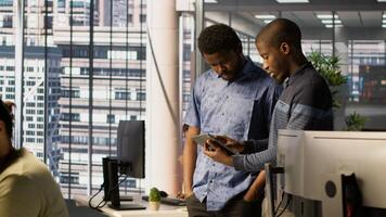 Technician and colleague using device for managing cloud computing platforms training machine learning models. IT staff members in office monitoring company systems using tablet, camera A photo