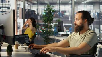 System administrator with disability in inclusive workspace training machine learning models. IT specialist with paraplegia monitoring and maintaining company systems, camera B photo
