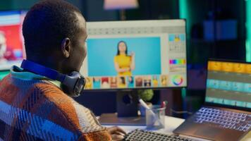 Black man photo editor in a well organized workspace editing images on dual monitors using advanced software tools, displaying creativity and professional dedication. Computer setup. Camera A.