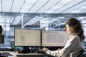IT engineer in data center using PC to find misconfigurations affecting rackmounts. Woman checking servers bottlenecks leading to sluggish data transfer rates, doing maintenance photo