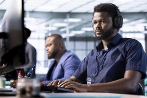 Man in data center wearing headphones to hear songs while creating technical documentation for software applications. IT expert listening music, working in server room, maintaining databases photo