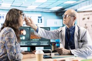 Medic expert uses a thermometer to find the right diagnostic and symptoms, working with modern tools to support healthcare industry on medical insurance services. Patient interaction. photo