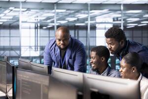 Management executive checking on data center employees creating technical documentation for software applications. Team leader supervising IT workers in server room maintaining databases photo