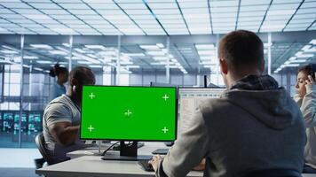 Engineer in server hub using green screen PC to repair equipment storing datasets. Professional using mockup computer to do debugging on rigs doing computational operations, camera B photo