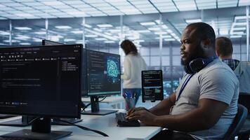 Engineer working in high tech establishment providing computing resources for different workloads. African american man tasked with monitoring data center supercomputers, camera B photo