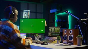 African american man editing film footage on his dual monitors, create content for cinematography next to copy space. Workspace organized for productivity, editing software and multitasking. Camera B. photo