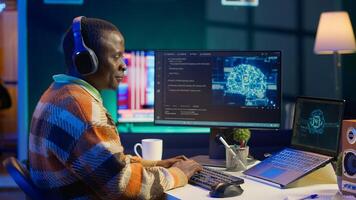 African american worker at desk using personal computer for programming and data analysis. Male networking expert working at home, manages information technology and data center on pc. Camera A. photo