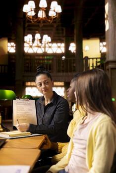 Female professor guiding primary school pupils on a team project, presenting a file to guide them towards assignment success. Effective tutoring techniques during private lessons. photo