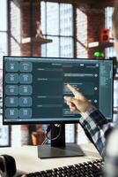Remote employee seated at desk getting help from AI LLM chatbot software in home office. Man pointing to screen, working with large language model program on computer monitor photo