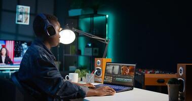 editor adds sound effects to filmed footage, working in home studio. Videographer using headphones to test and improve audio quality, editing clips with professional software, camera B photo