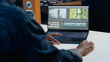 editor trimming segments of drone shot footage, working on promotional clip in home office. Videographer splicing film pieces, editing them using professional software on laptop, camera A photo