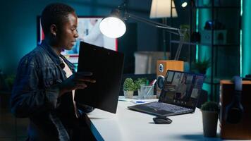 Manager talking with collaborator working from home, holding teleconference meeting to present project. Team leader talking with employee showing charts on clipboard during online videocall, camera A photo