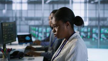 African american data center technicians implement AI predictive maintenance systems. Woman in server hub using artificial intelligence to identify hardware failures, camera A photo