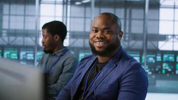 Portrait of happy server room worker developing disaster recovery plans ensuring minimal downtime. Smiling technician in data center using data analytics to monitor performance, camera A photo
