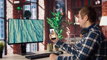 Man in home office looking at social media feed with live broadcasts from online content creators. Employee at work using social network application with livestreams done by influencers, camera A photo