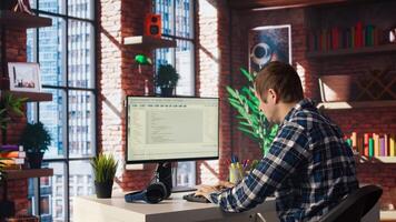 Man in home office looking at UI on PC screen, typing and executing programming code. Coding application UI used by IT developer writing and testing code in modern workspace, camera A photo